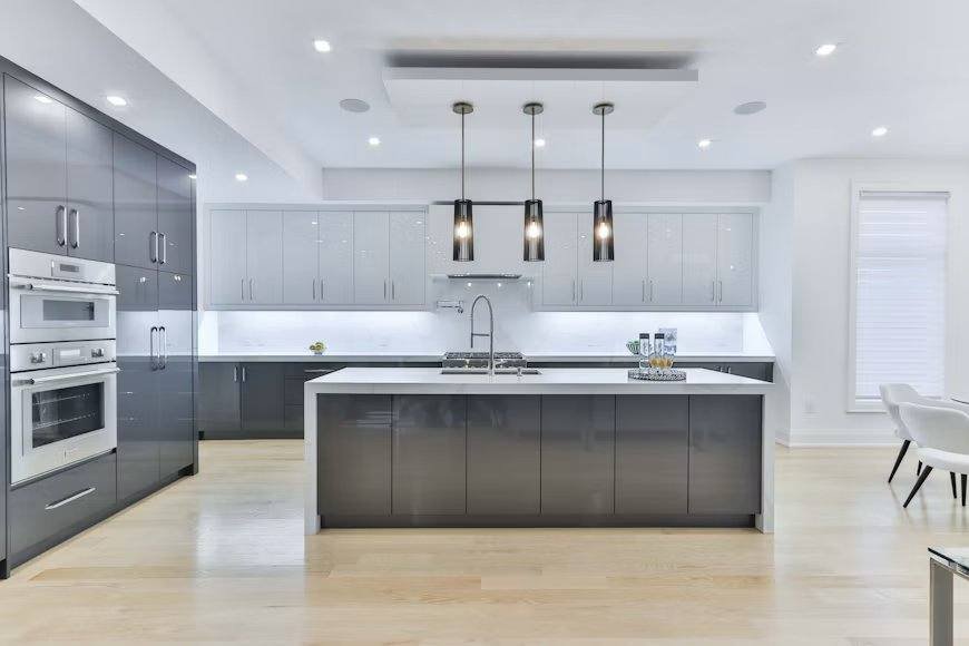 Cozinha planejada moderna com ilha central cinza, armários até o teto e fornos embutidos